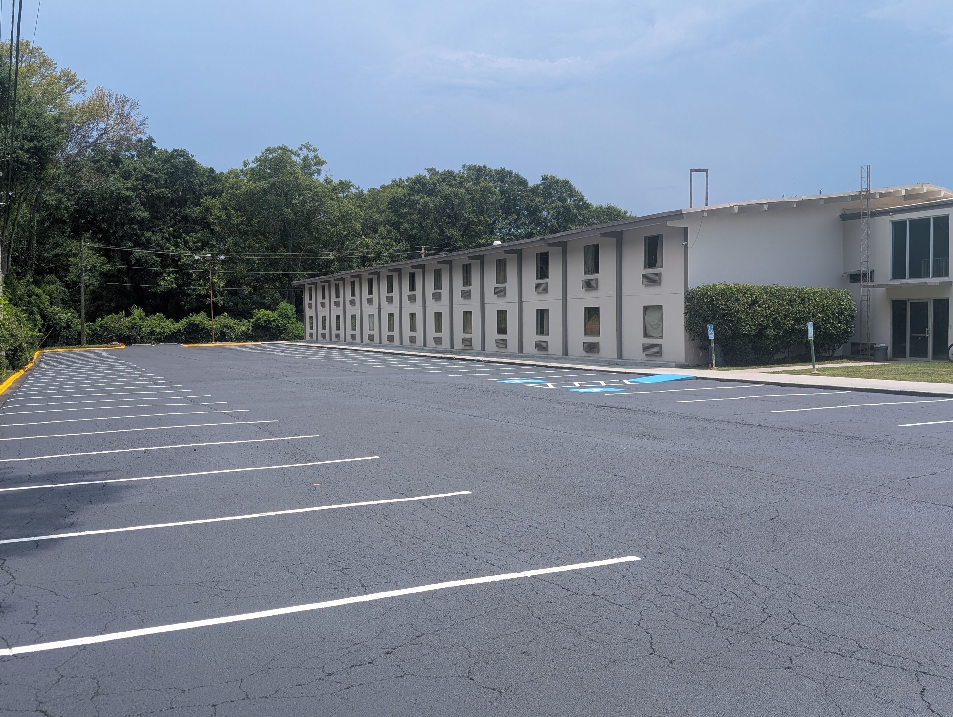 A parking lot with marked spaces, a building with multiple windows, and a clear sky.