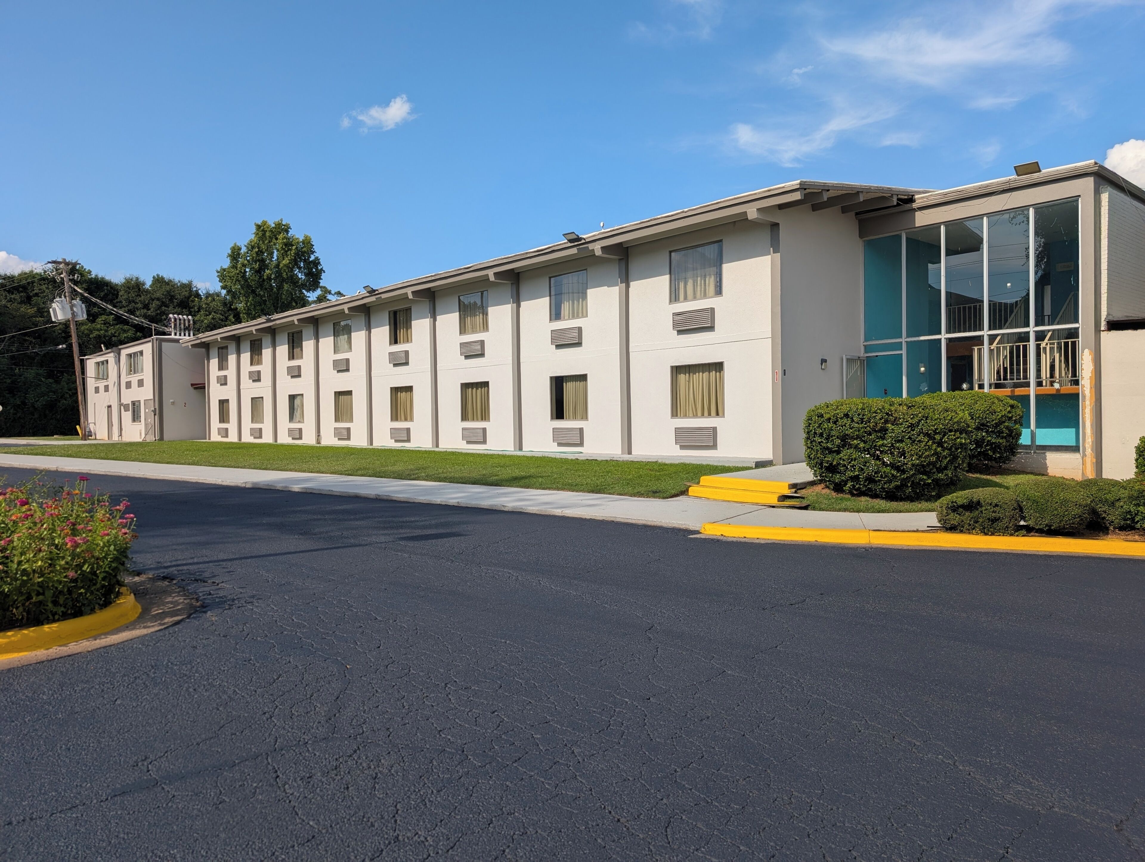 A multi-story hotel with a flat facade, large windows, and a parking lot in front.