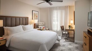 A hotel room with a large bed, a desk, a chair, a ceiling fan, and a television. - Marriott Shadow Ridge The Enclaves COACHELLA STAGECOACH (Palm Desert)