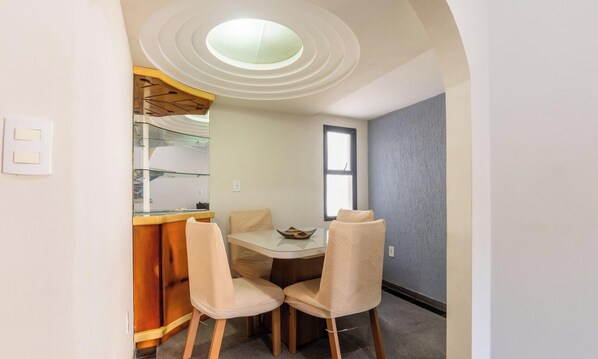 Un coin repas compact comprenant une table ronde et deux chaises, un petit comptoir de bar et une fenêtre.