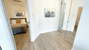 Une chambre à coucher moderne avec un lit, une table de chevet et un miroir.