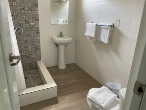 Un baño con ducha, lavabo e inodoro.