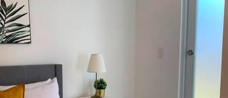 A bedroom with a bed, a nightstand, a lamp, and a window.