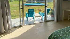 A room with a sliding glass door leading to a backyard with a pool and outdoor furniture. - Savannah Studio Apart Queen Size Bed - 2 Guest 102 (San Andrés y Providencia)