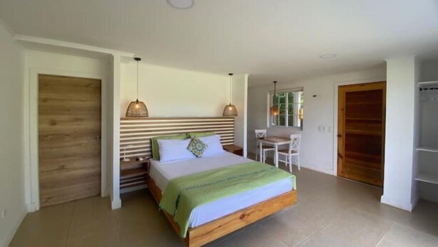 A bedroom with a bed, bedside tables, a window, and a door. - Savannah Studio Apart Queen Size Bed - 2 Guest 102 (San Andrés y Providencia)