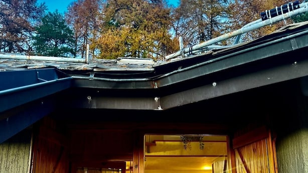 Una cabaña rústica con fachada de madera, un área de cocina visible y un ventanal grande.