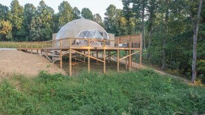 A geodesic dome structure with a wooden deck and outdoor seating area, surrounded by forest. - The Dome At The Ridge-A Glamping Experience On The Bourbon Trail (Raywick)