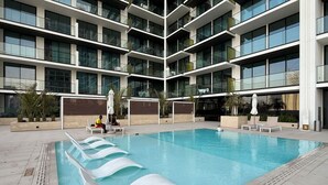 Un edificio moderno con una amplia piscina interior, varios balcones y zonas de estar al aire libre.