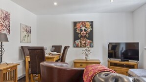 Una sala moderna con comedor, televisión de pantalla plana y obras de arte en las paredes.