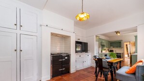 A spacious kitchen with white cabinets, a dining area with a table and chairs, and a hanging light fixture. - Central Caversham / Traditional English House | Pass the Keys (Reading)