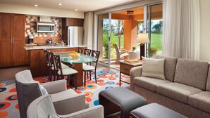 A modern kitchen with a glass dining table, a sofa, and a view of the outdoors.