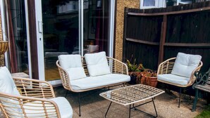 A patio area with wicker furniture, including two chairs and a small table. - Cosy Home w/ Stylish Interior – PassTheKeys (Watford)