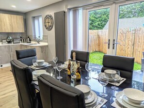 A dining area with a glass table, black chairs, and a bottle of champagne.