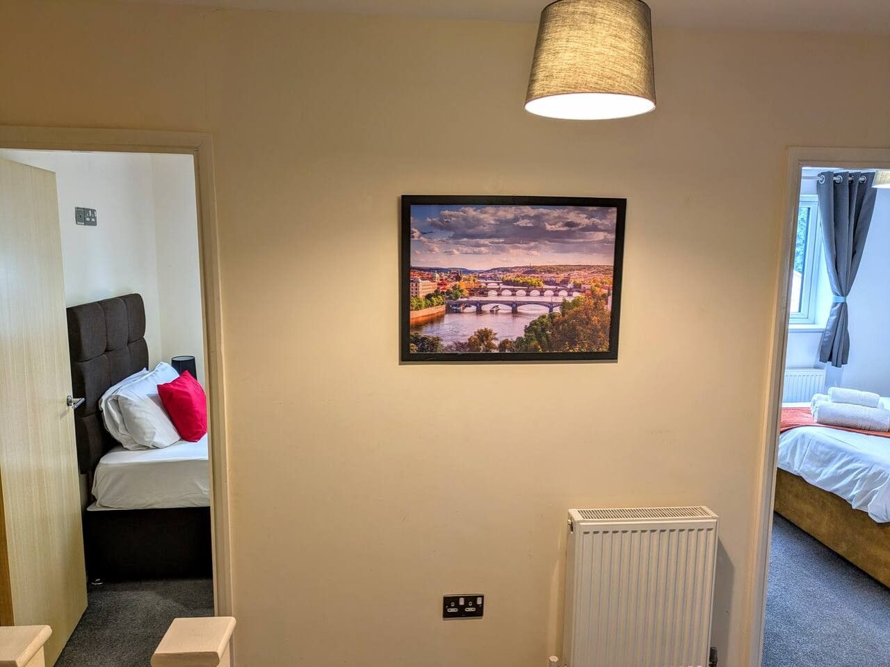 A hotel room with a bed, a radiator, and a framed picture on the wall.