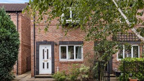 A brick house with a white front door, a small garden with gravel, and a black metal fence. - Beautiful Renovated Central Home in York with Free Parking | Pass The Keys (York)