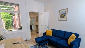 A living room with a blue sofa, a wooden table, and a patterned rug. - Contractors 4BR Home, Newly Refurb, Nr Centre (West Midlands)