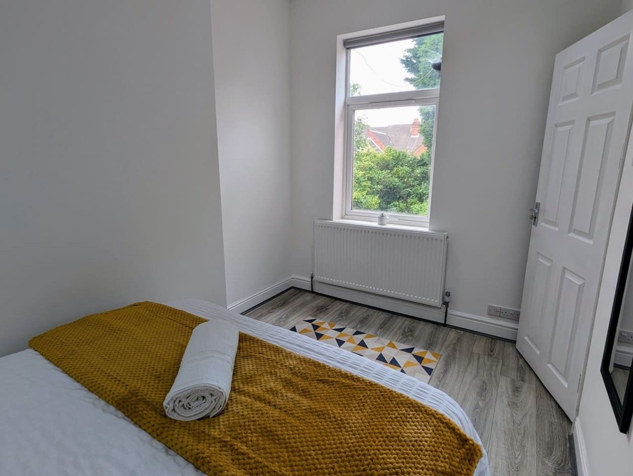 A small, clean room with a bed, a window, and a radiator.