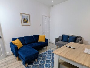 A living room with a blue sofa, a grey sofa, a wooden coffee table, and a patterned rug. - Contractors 4BR Home, Newly Refurb, Nr Centre (West Midlands)