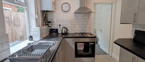 Una cocina compacta con estufa a gas, horno y ventana que proporciona luz natural.