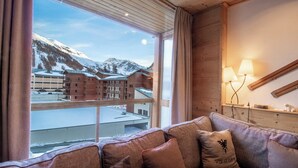 Una habitación acogedora con un ventanal que ofrece vistas a una estación de esquí y montañas.