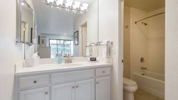 A modern bathroom with a large vanity, a walk-in shower, and a toilet.