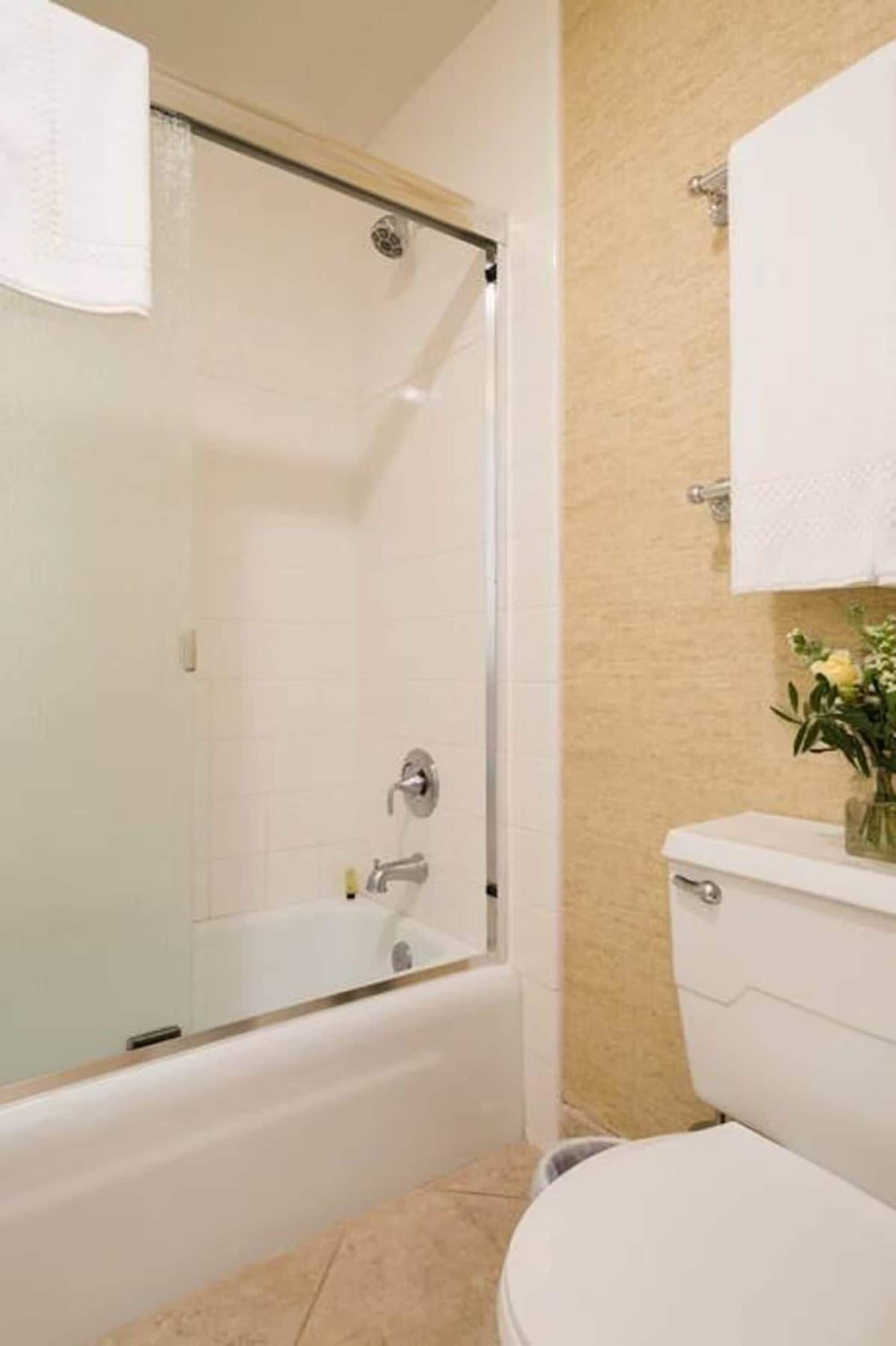 A bathroom with a glass-enclosed shower, a white toilet, and a beige tiled wall.