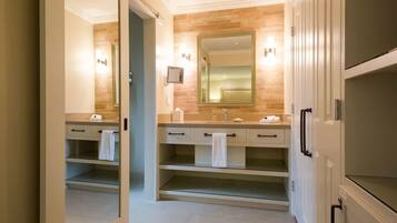 A modern bathroom with a large mirror, two sinks, and a walk-in shower.