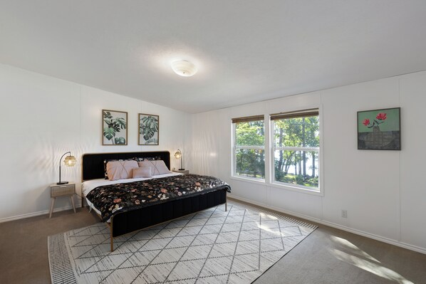 Un dormitorio con cama, mesita de noche, lámpara, ventana y decoración en la pared.
