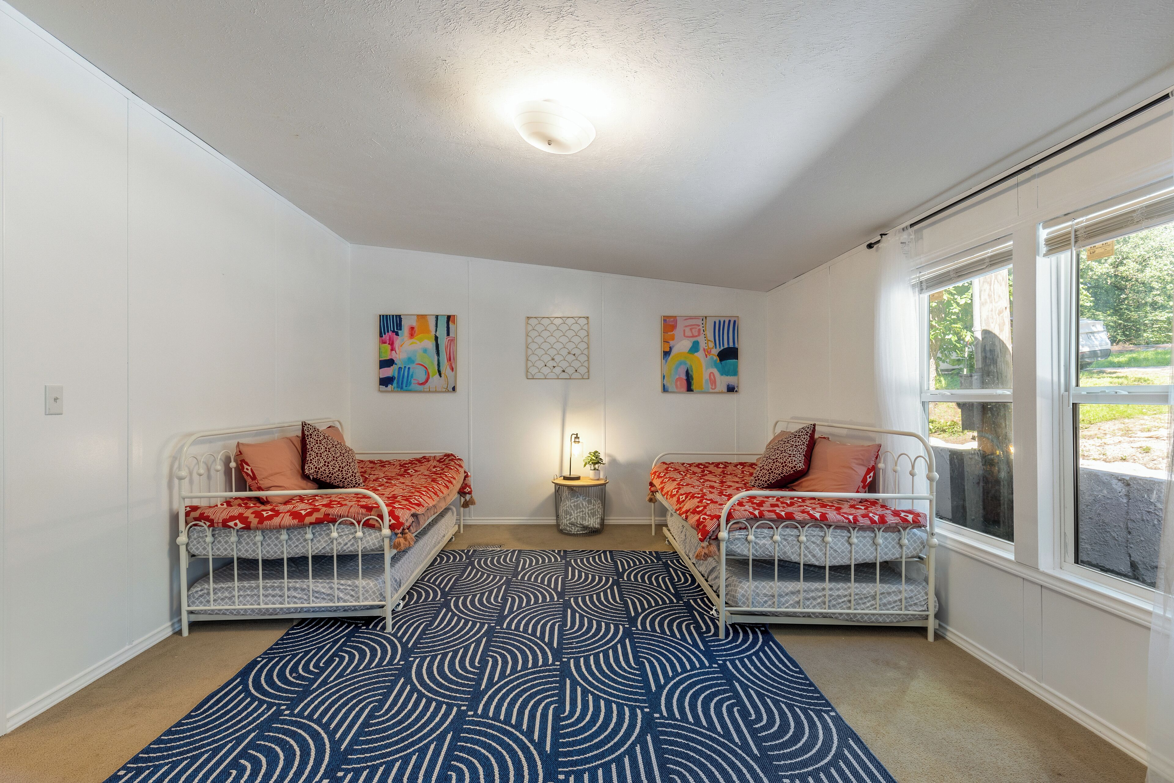 A room with two metal bunk beds, a patterned rug, and artwork on the walls.