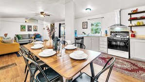 Een moderne keuken met witte kasten, een houten eettafel voor vier personen en een inbouwoven.