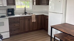 Una cocina moderna con armarios de madera oscura, un refrigerador blanco, una cafetera y una ventana con persianas.