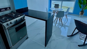 A modern kitchen with a gas stove, a built-in oven, and a dining area with a table and chairs.