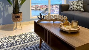 A living room with a large window, a sofa, a coffee table, and a potted plant.