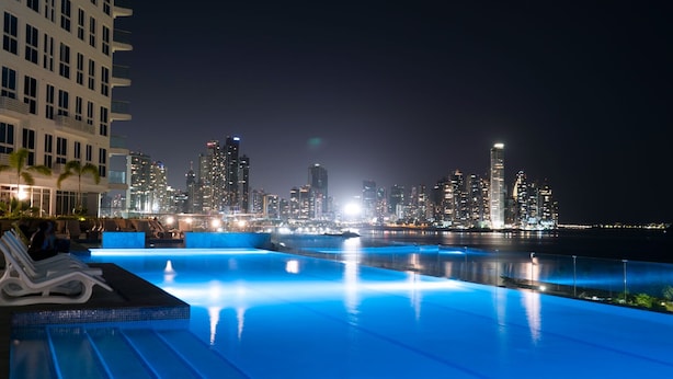 A nighttime view of a swimming pool with a city skyline in the background.