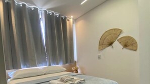 A modern bedroom with a large bed, grey curtains, and two wall fans. - Edifício Tours Du Porto (Ipojuca)