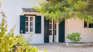 A white building with green shutters, a small tree, and a number '11' on the wall.