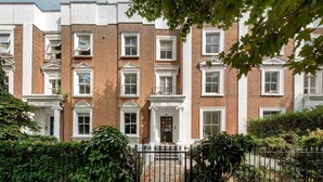A row of red brick townhouses with white window frames and a black metal gate. - Modern 2 bed Flat - Hammersmith Grove (London)