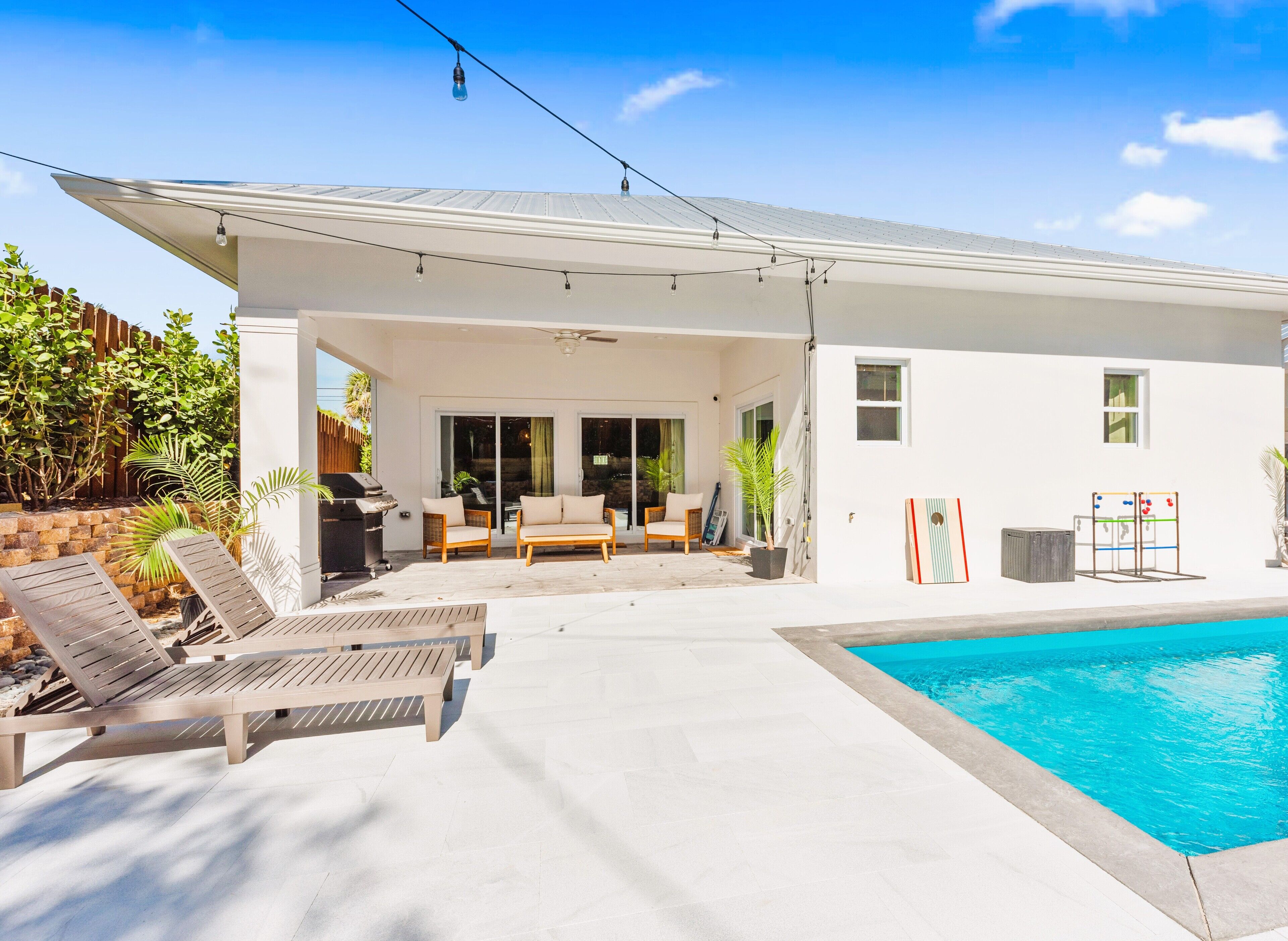 A modern house with a pool, outdoor furniture, and a patio area.