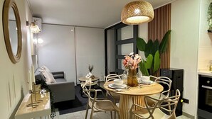 Una zona de menjador moderna amb una taula rodona, cadires blanques i un llum penjant.