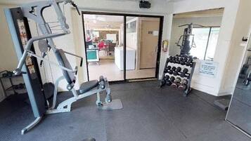 Une salle de sport équipée de matériel d’exercice, avec un porte-haltères et une porte donnant sur une autre pièce.