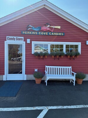 A candy store with a red exterior, a white bench, and potted plants. - "Leaf Peeping" Season, Fall Colors, Fairs & Family (Wells)