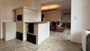 Eine moderne Küche mit einer zentralen Kochinsel, ein Essbereich mit Tisch und Stühlen, und ein Flur, der in ein weiteres Zimmer führt.