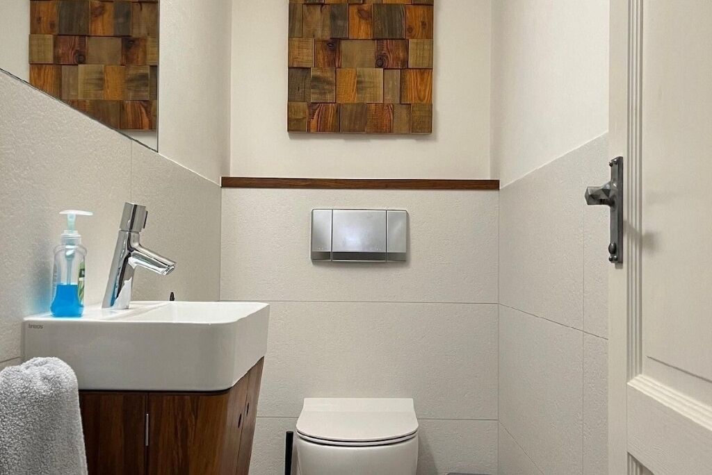 A bathroom with a white sink, a toilet, and a wall-mounted light fixture.