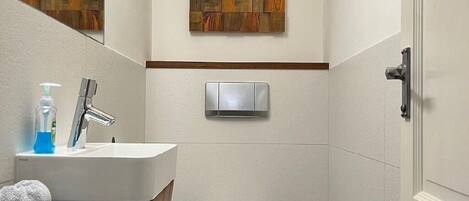 A bathroom with a white sink, a toilet, and a wall-mounted light fixture.