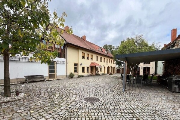 A cobblestone courtyard with a building featuring a red-tiled roof and a yellow facade. - Spacious holiday home in Dresden for up to 12 people with 6 bedrooms (Dresden)
