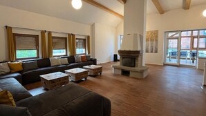 Ein geräumiges Wohnzimmer mit Kamin, einer Sofagarnitur und großen Fenstern.