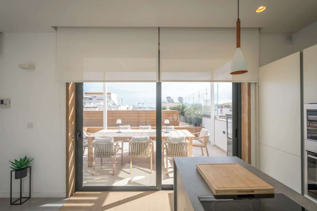 A modern kitchen with a large window, a dining area with wooden furniture, and a view of the cityscape.