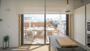 A modern kitchen with a large window, a dining area with wooden furniture, and a view of the cityscape. - Sky villa penthouse, private pool | MIL by Homega (St. Julian's)