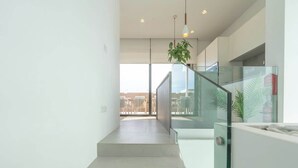 A modern staircase with glass railings, a view of the city, and a hanging plant. - Sky villa penthouse, private pool | MIL by Homega (St. Julian's)