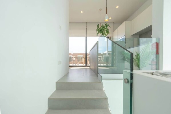 A modern staircase with glass railings, a view of the city, and a hanging plant. - Sky villa penthouse, private pool | MIL by Homega (St. Julian's)